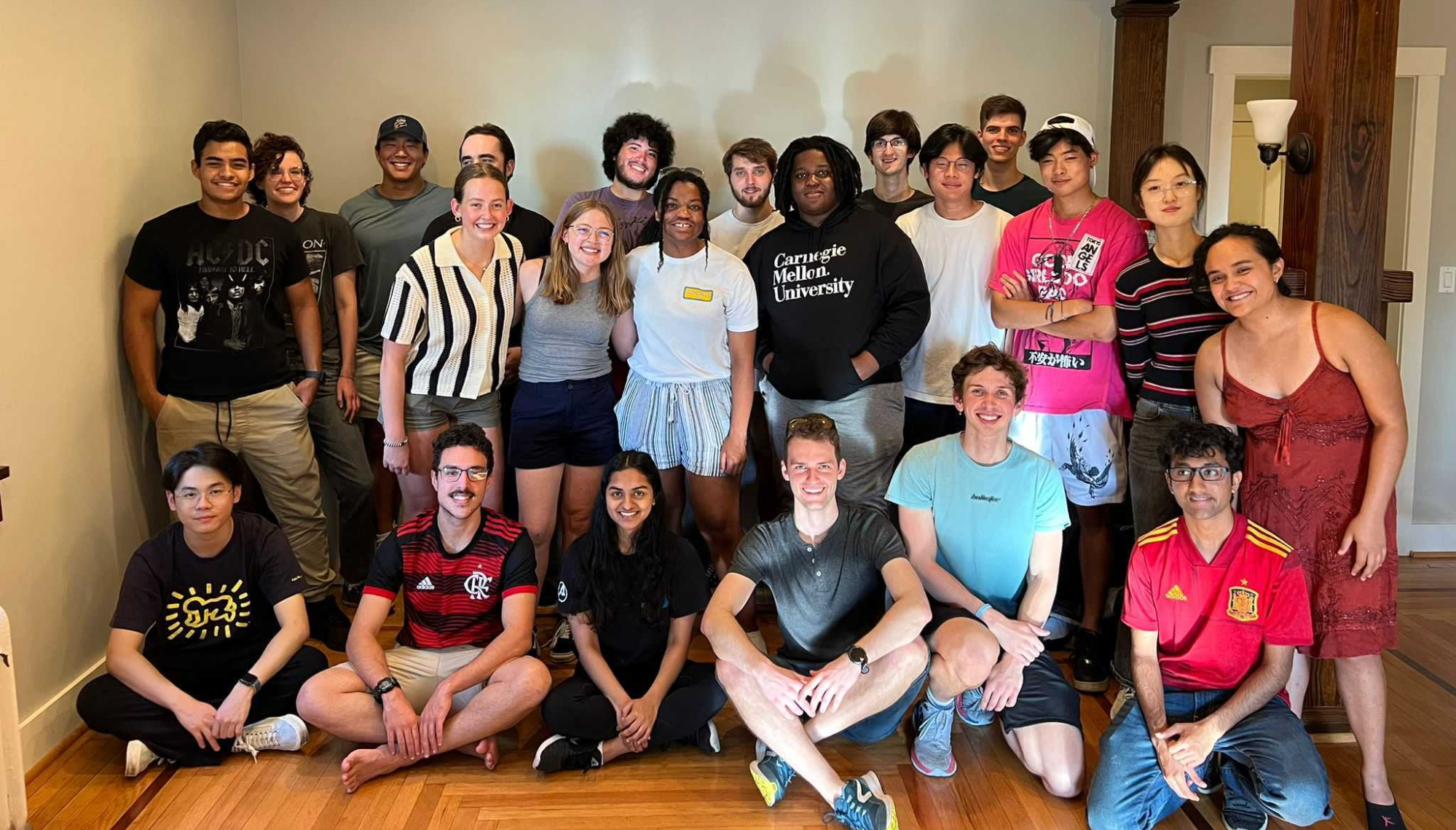 Twenty-one students casually posed together in a Pittsburgh home